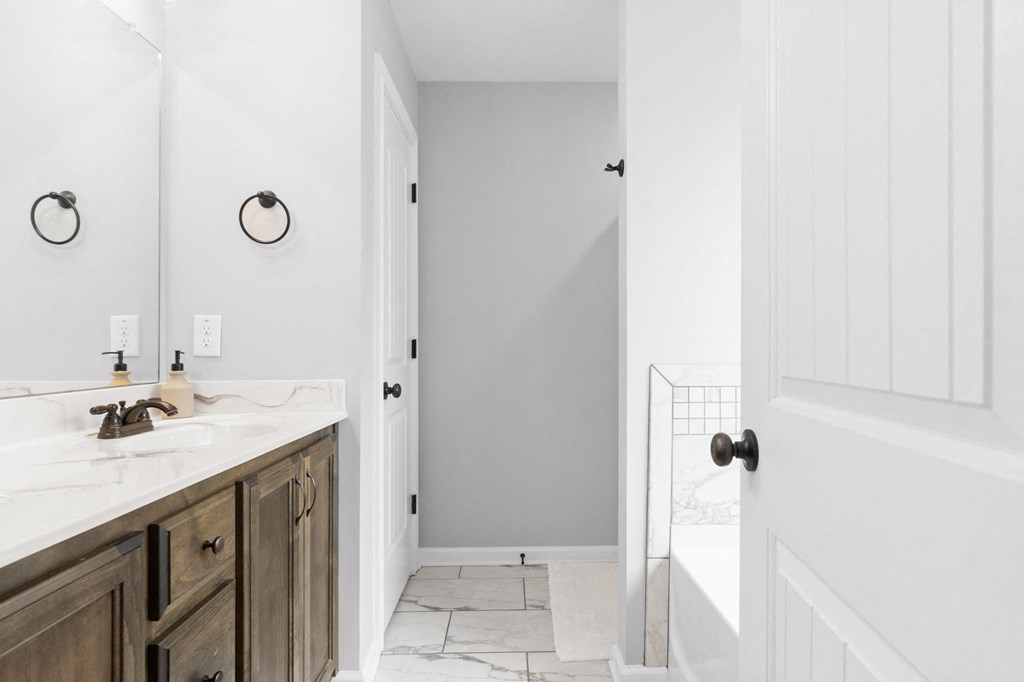 a white bathroom with a sink and a tub and a mirror