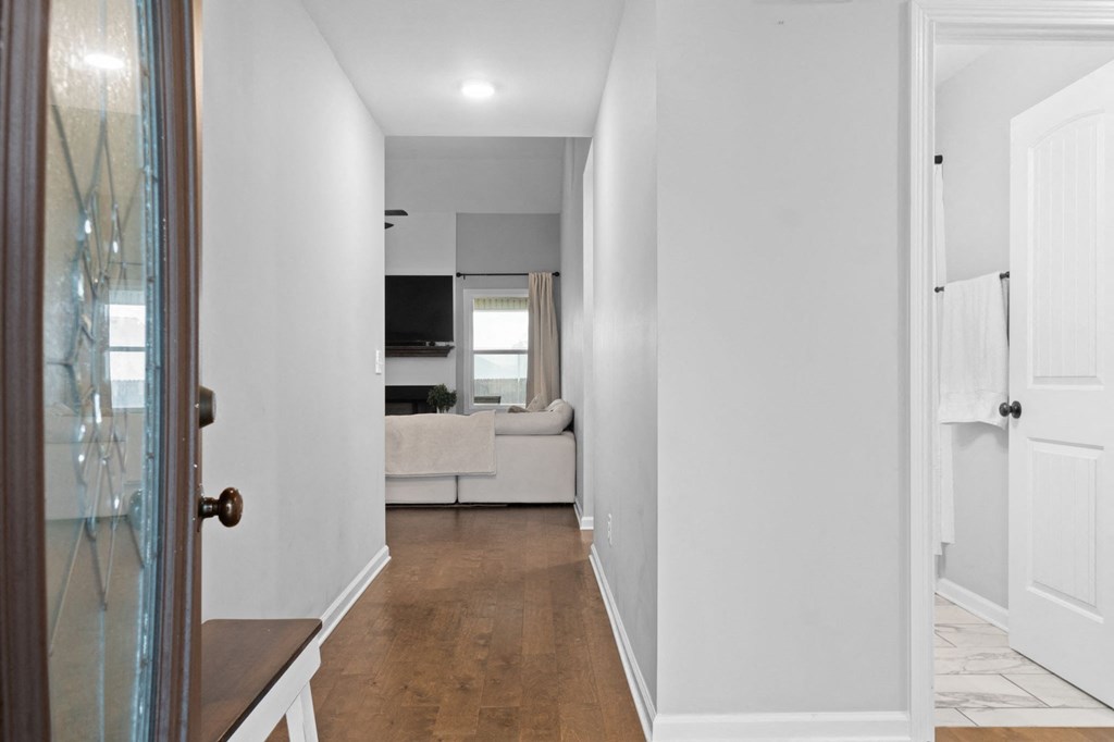 a hallway with a door to a living room with a couch and a tv