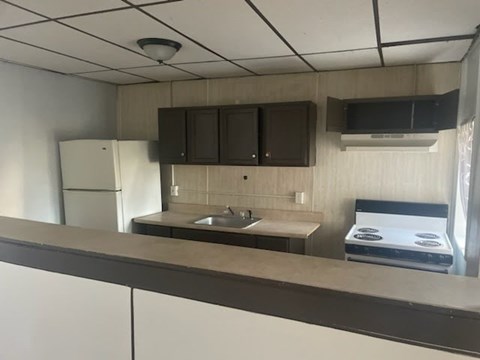 A kitchen with a white refrigerator, brown cabinets, and a stove top oven.