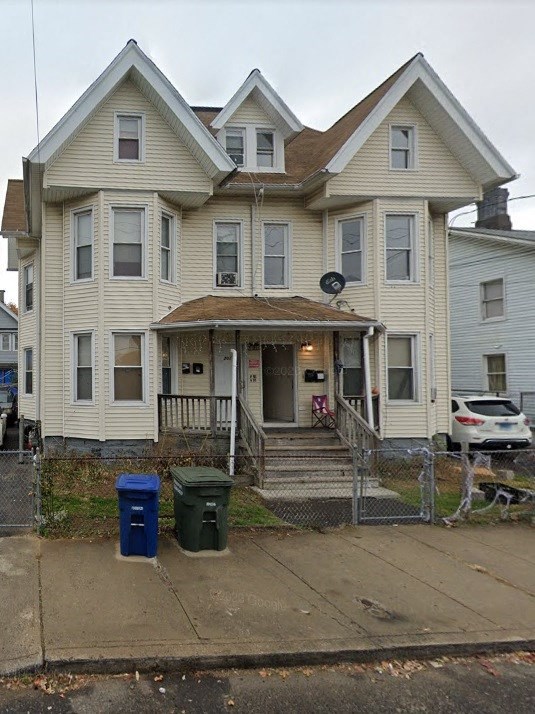 a yellow house with a blue trash can in front of it