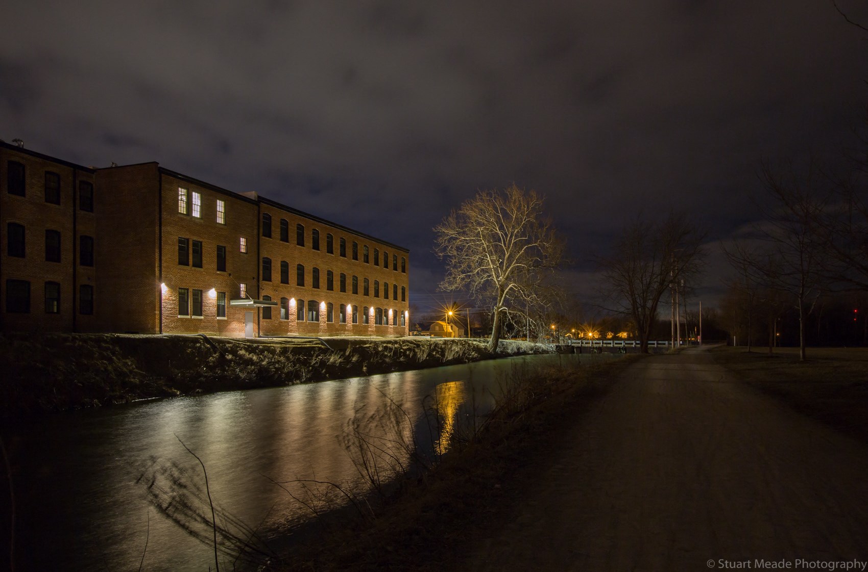 a city street at night with buildings and a river