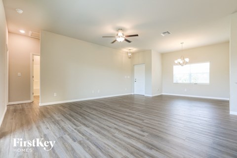 A spacious room with wooden flooring and a ceiling fan.