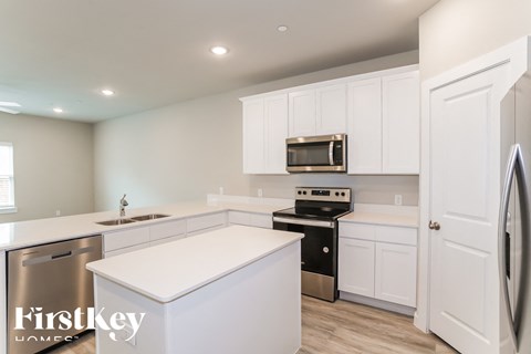 A kitchen with white cabinets and appliances, including a stainless steel refrigerator.
