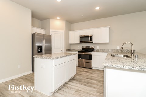 A kitchen with white cabinets and a granite countertop.
