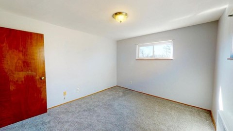 an empty room with a red door and a window