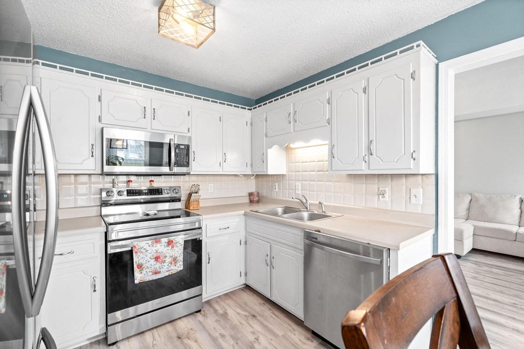 a kitchen with white cabinets and stainless steel appliances