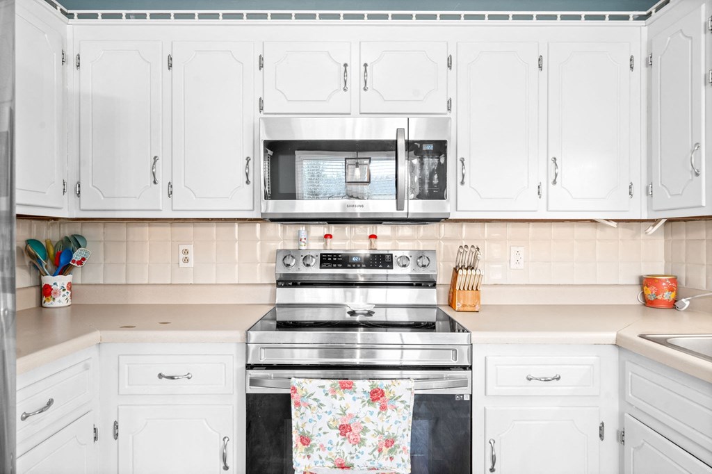a kitchen with white cabinets and a stove and a microwave