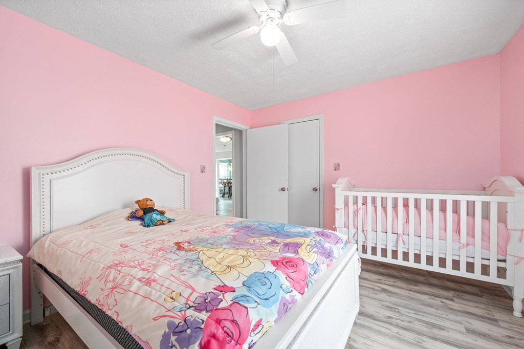 a bedroom with a bed and a crib and a ceiling fan