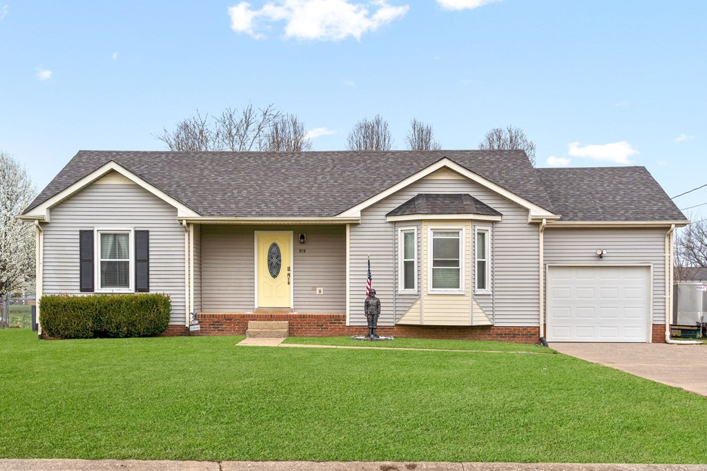a beige house with a yellow door and a lawn
