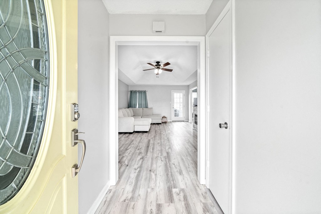 a living room with white walls and a yellow door and a ceiling fan