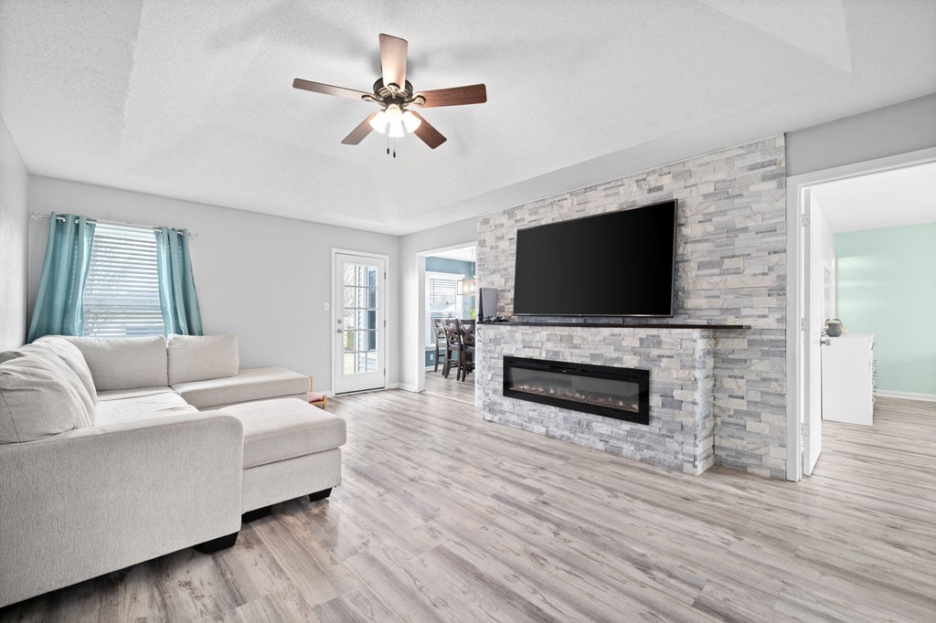 a living room with a fireplace and a ceiling fan