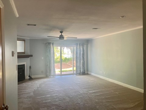 A room with a ceiling fan and sliding glass doors.