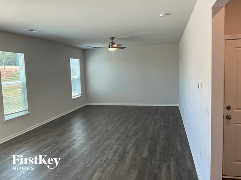 an empty living room with wood floors and a ceiling fan