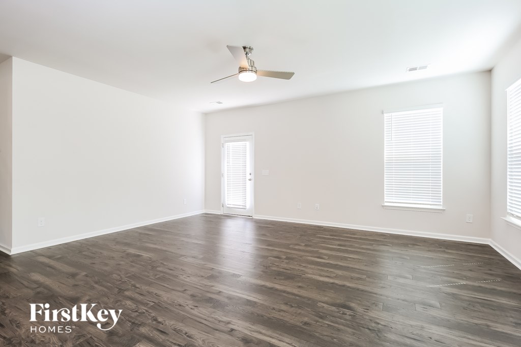 A spacious room with wooden flooring and a ceiling fan.