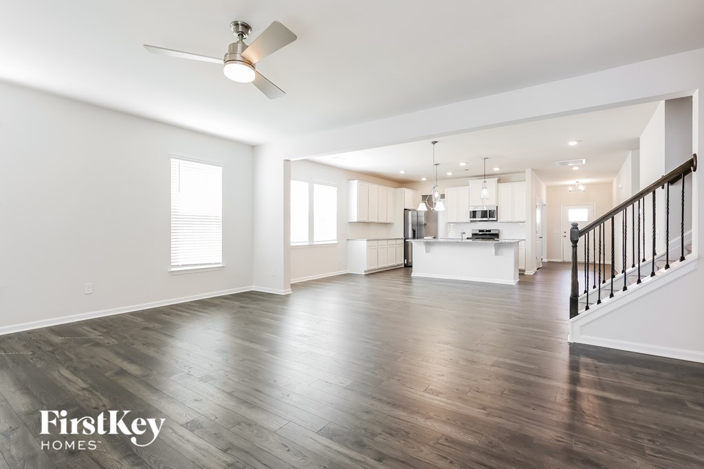 A spacious living room with wooden floors and a ceiling fan.