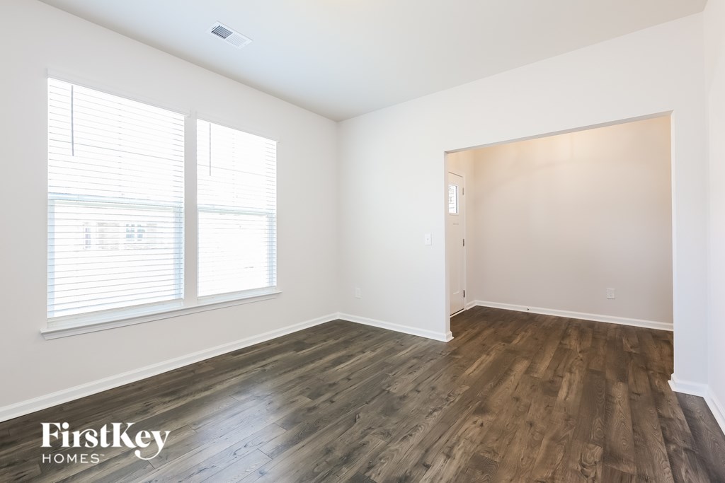 A room with wooden flooring and a window with blinds.