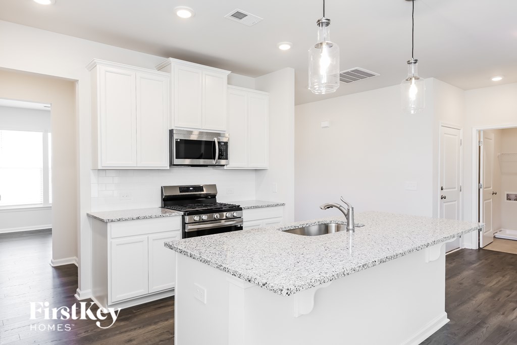 A kitchen with a granite countertop and a stove top oven.