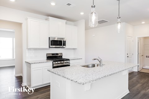 A kitchen with a granite countertop and a stove top oven.
