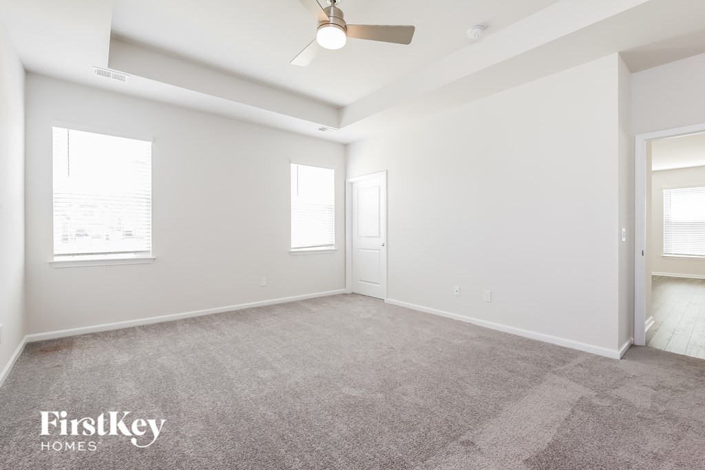 A spacious room with a carpeted floor and a ceiling fan.