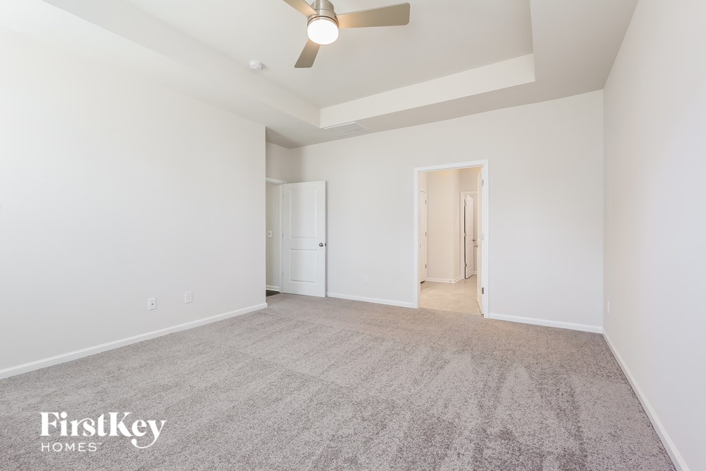 A spacious room with a carpeted floor and a ceiling fan.