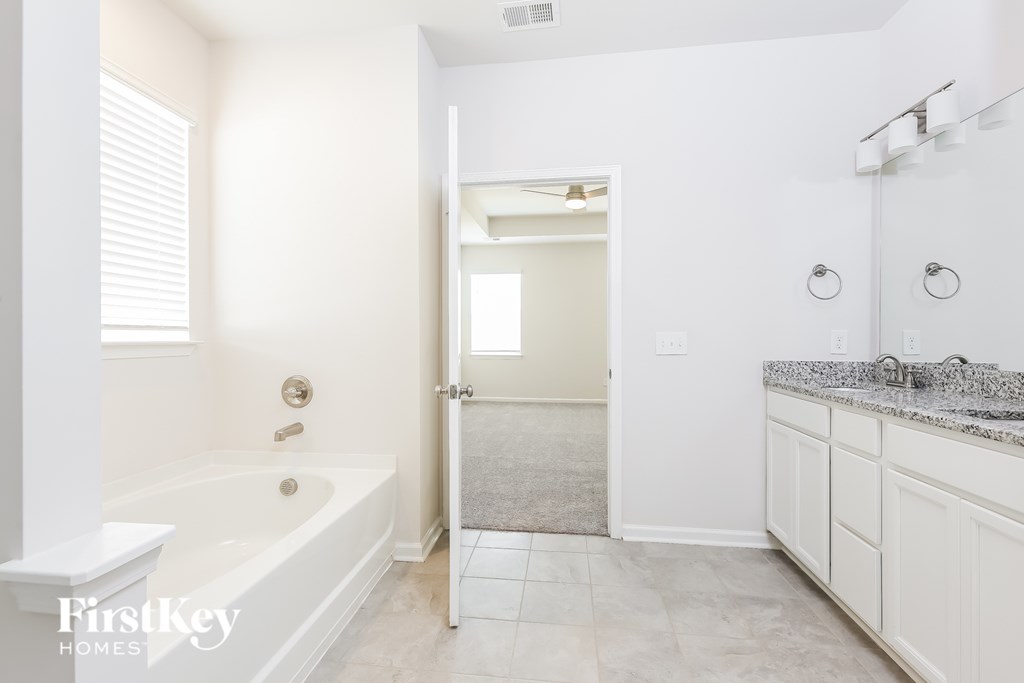 A white bathroom with a tub, sink, and mirror.