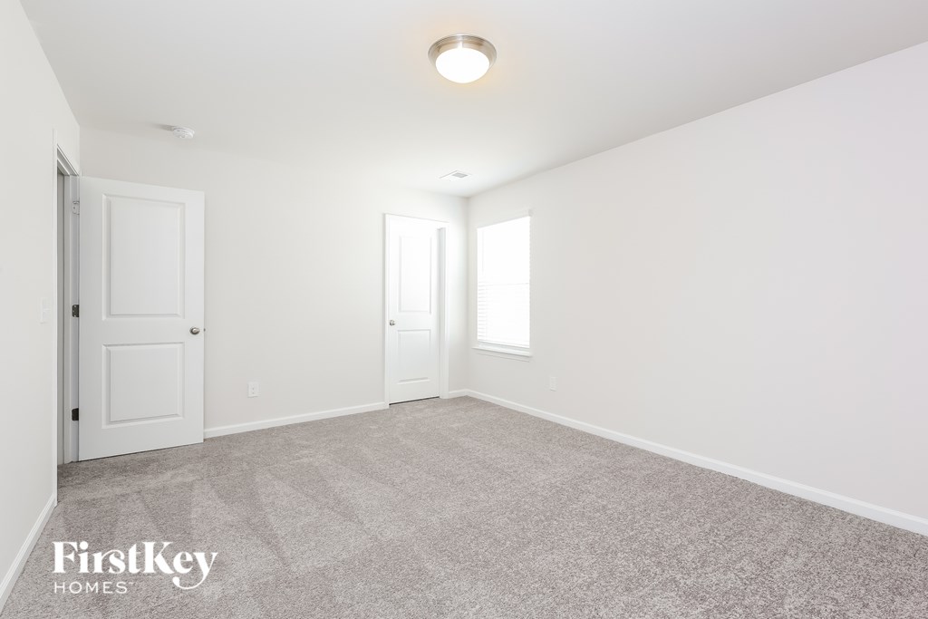 A carpeted room with a door and a window.