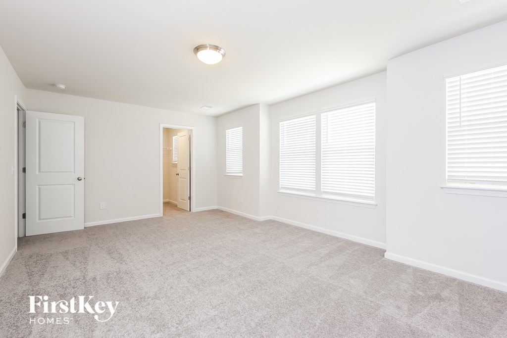 A spacious room with a carpeted floor and white walls.