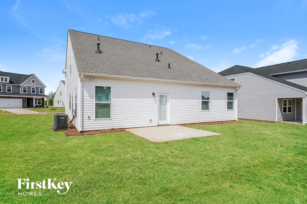 A white house with a grey roof and a green lawn in front.