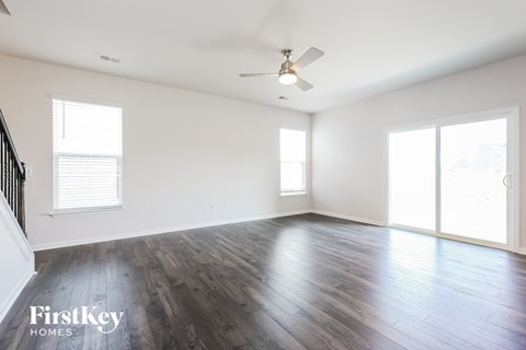 A spacious room with wooden floors and a ceiling fan.