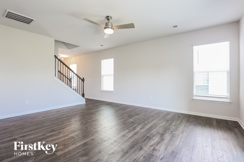 A spacious room with wooden floors and a staircase.