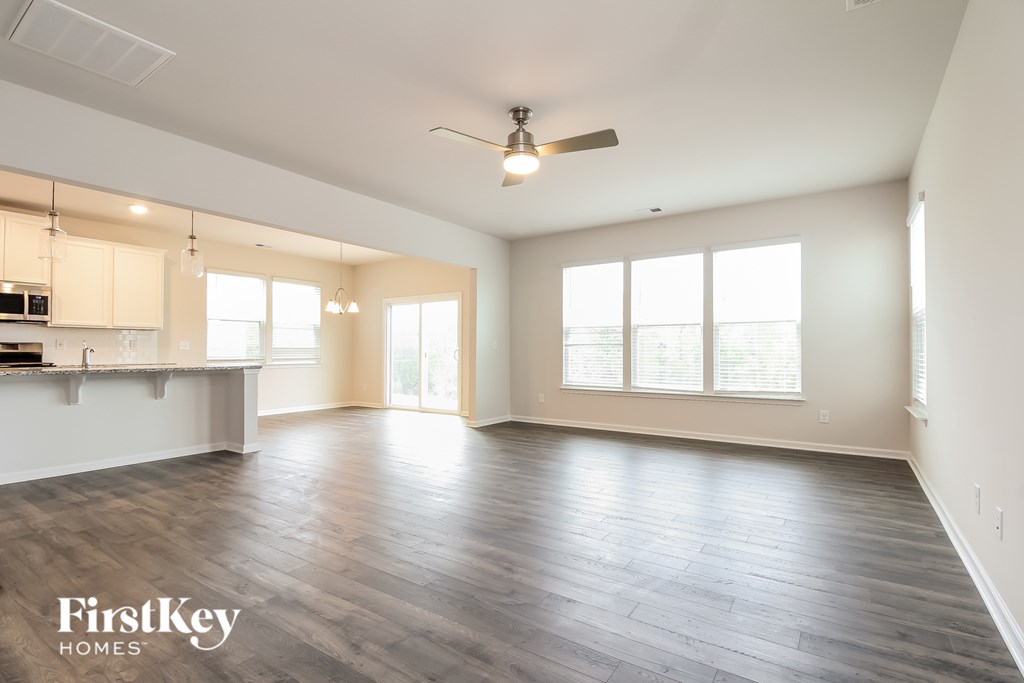 A spacious room with wooden flooring and a ceiling fan.