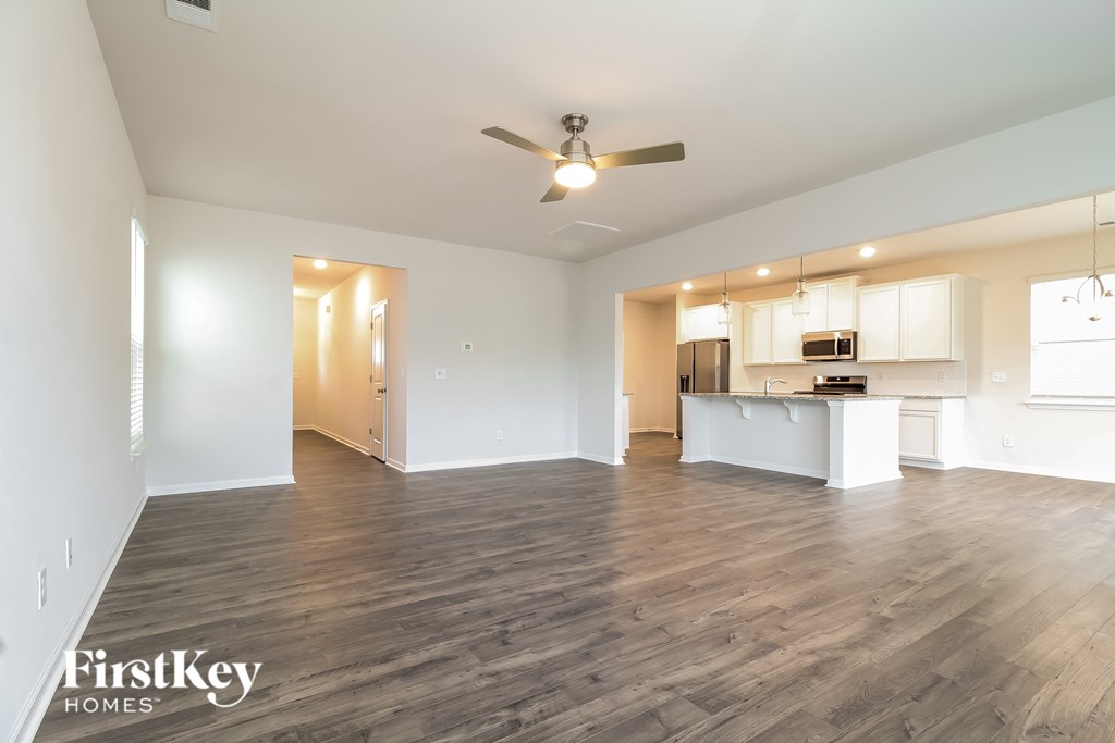 A spacious room with wooden flooring and a ceiling fan.