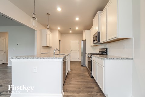 A kitchen with white cabinets and a white island with a FirstKey HOMES logo.