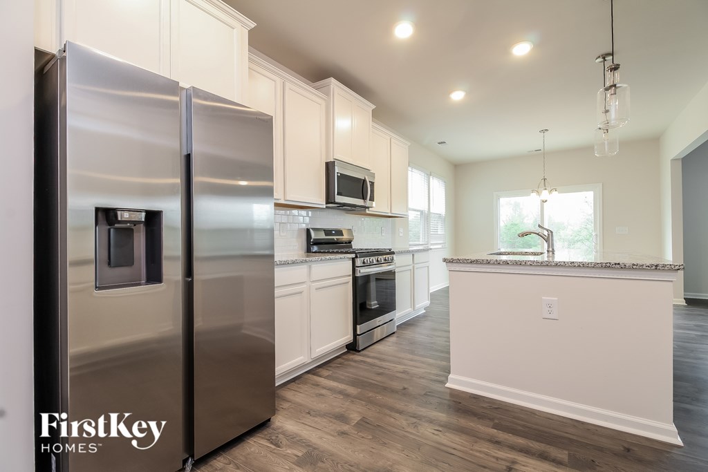 A modern kitchen with a stainless steel refrigerator and wooden floors.