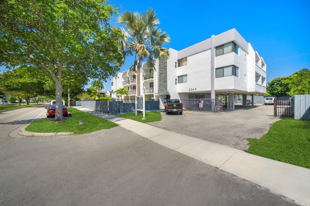 a large white building with palm trees and cars parked in front of it
