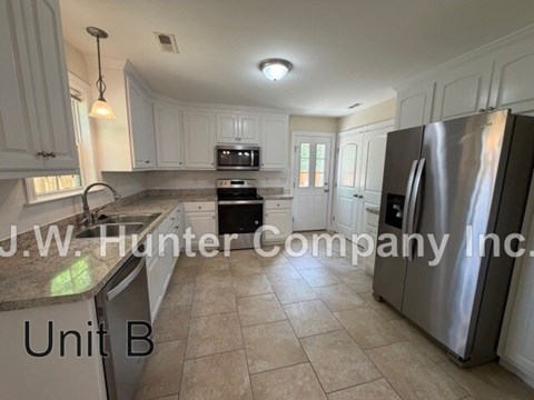 A kitchen with white cabinets and a stainless steel refrigerator.