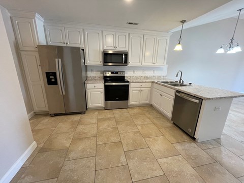 A kitchen with a refrigerator, oven, and microwave.