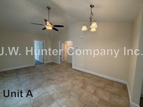 A room with a ceiling fan and light fixture, and a doorway leading to another room.
