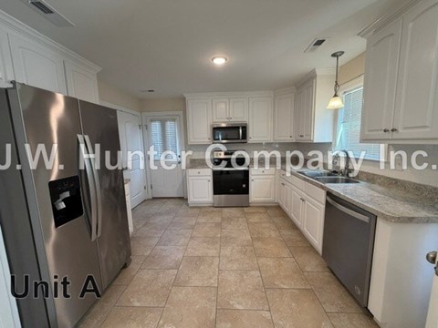 A kitchen with a stainless steel refrigerator and white cabinets.