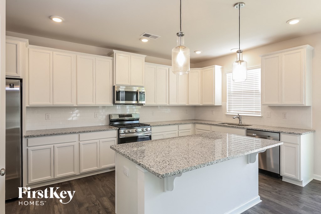 a white kitchen with granite counter tops and white cabinets