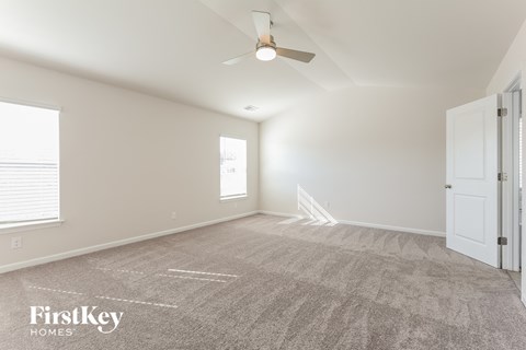 a spacious living room with carpet and a ceiling fan