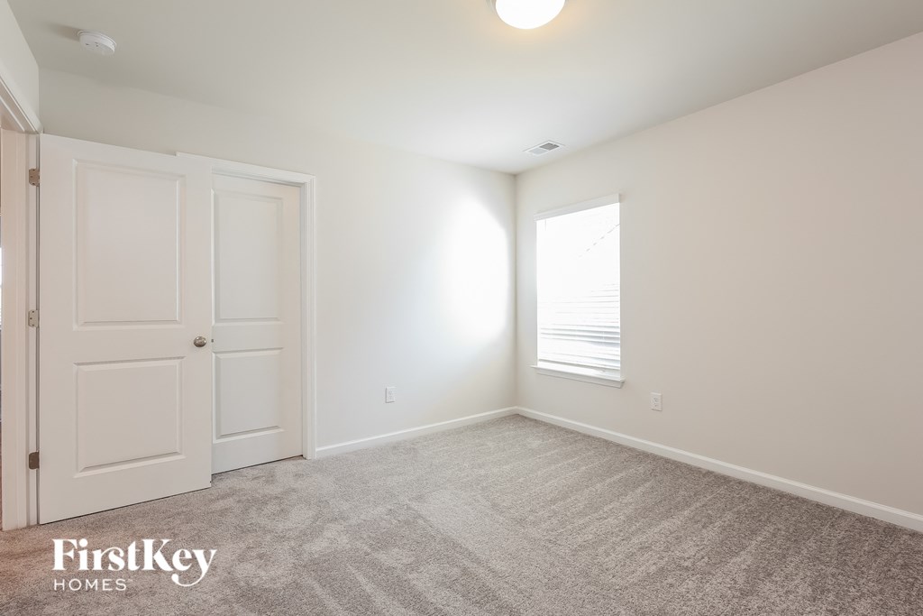 a bedroom with white walls and a white door and a window