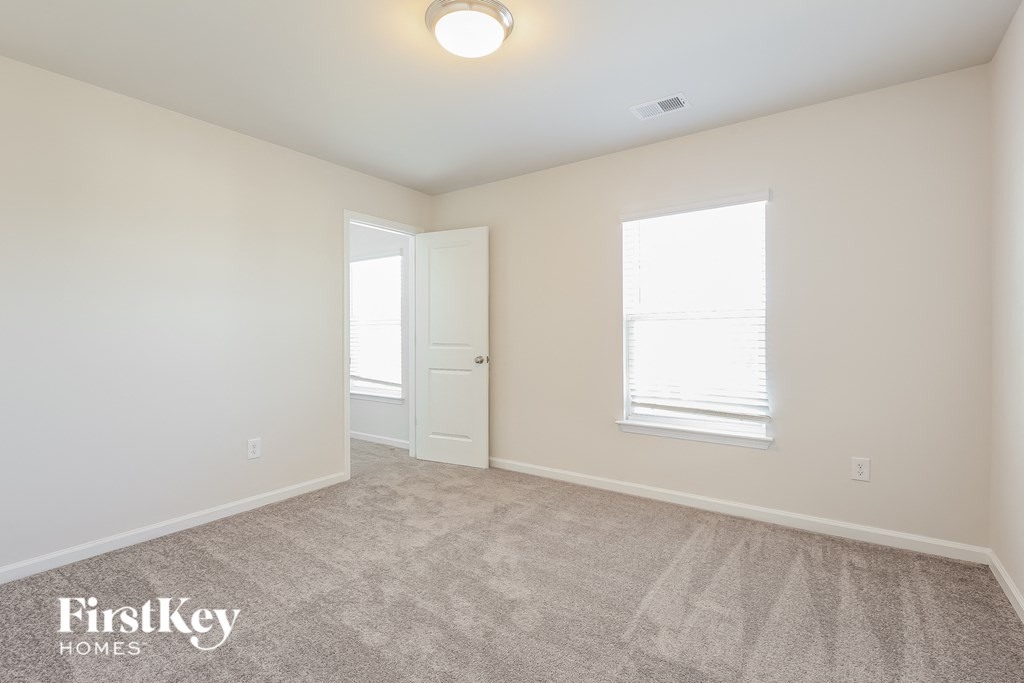a spacious living room with carpet and a door to a bedroom