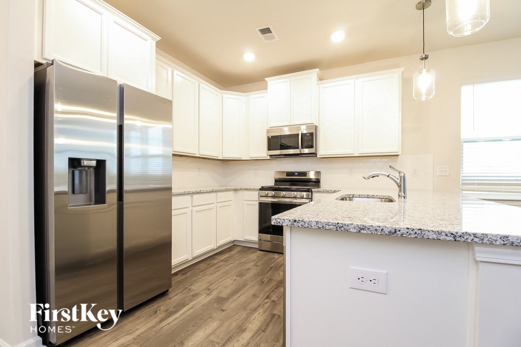 a white kitchen with stainless steel appliances and a marble counter top