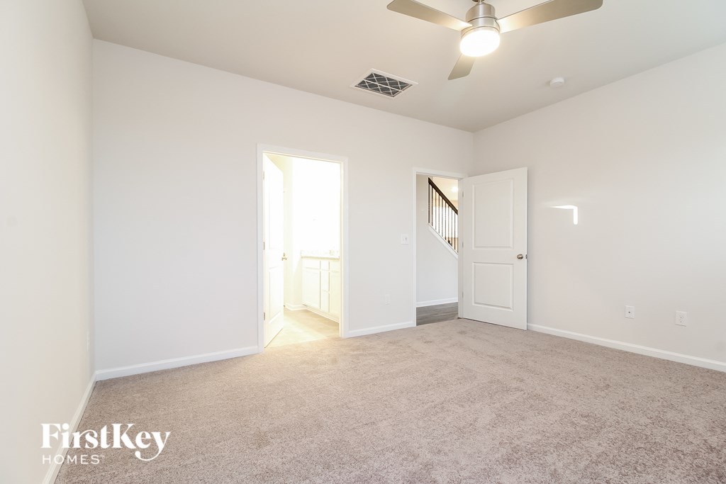 a spacious living room with carpet and a ceiling fan