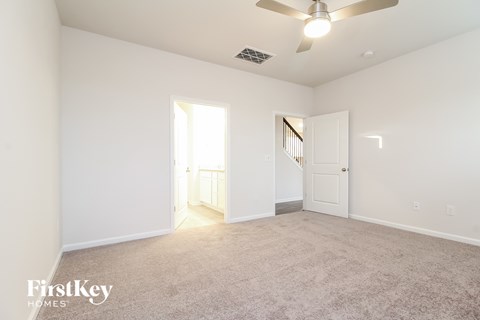 a spacious living room with carpet and a ceiling fan