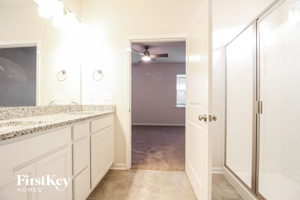 a bathroom with white cabinets and a shower and a sink