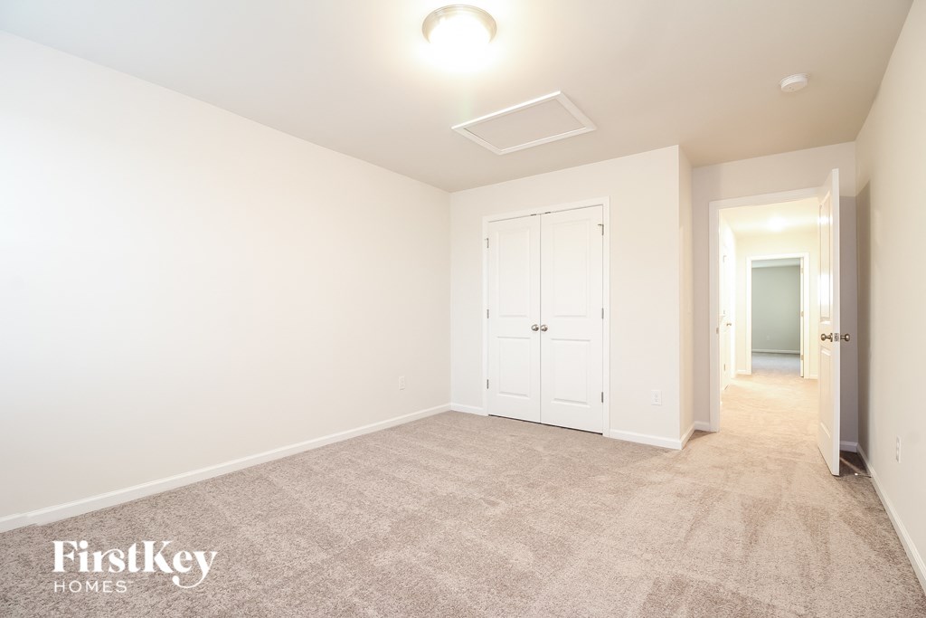 a white room with a carpeted hallway and a door to a closet