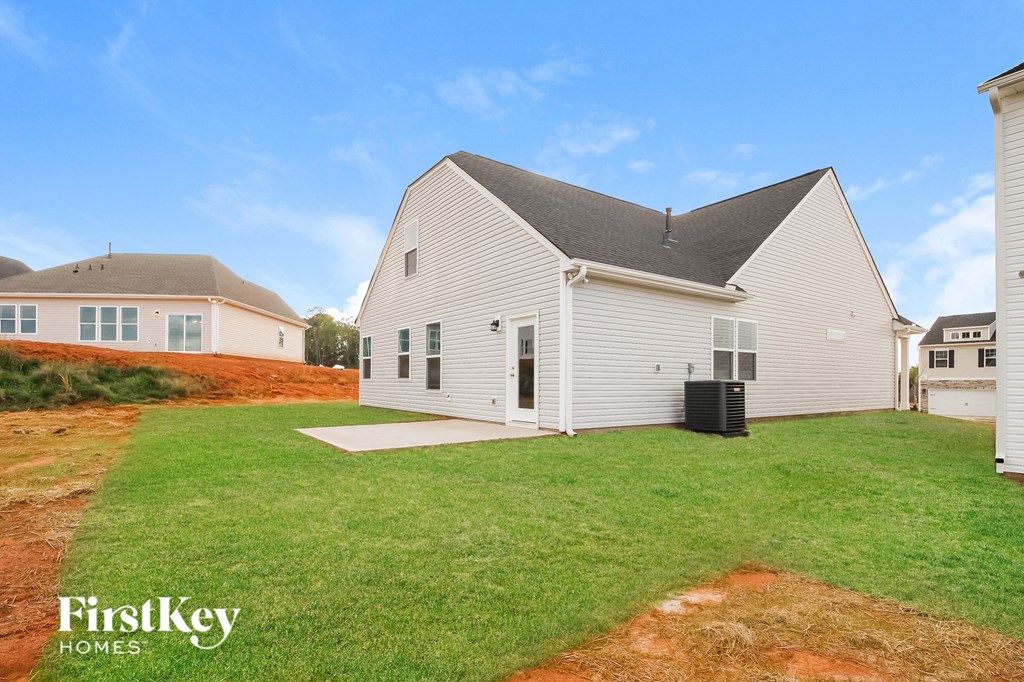 a backyard with a white house and a green lawn