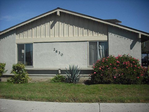 the front of a house with flowers in the yard